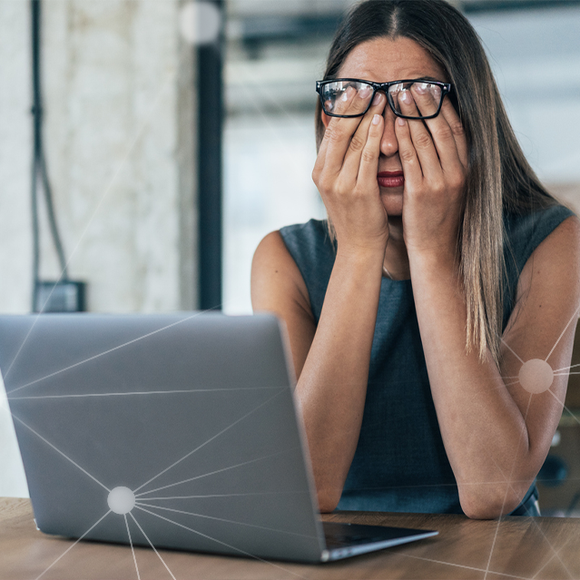 Woman Rubbing Her Eyes Behind a Laptop